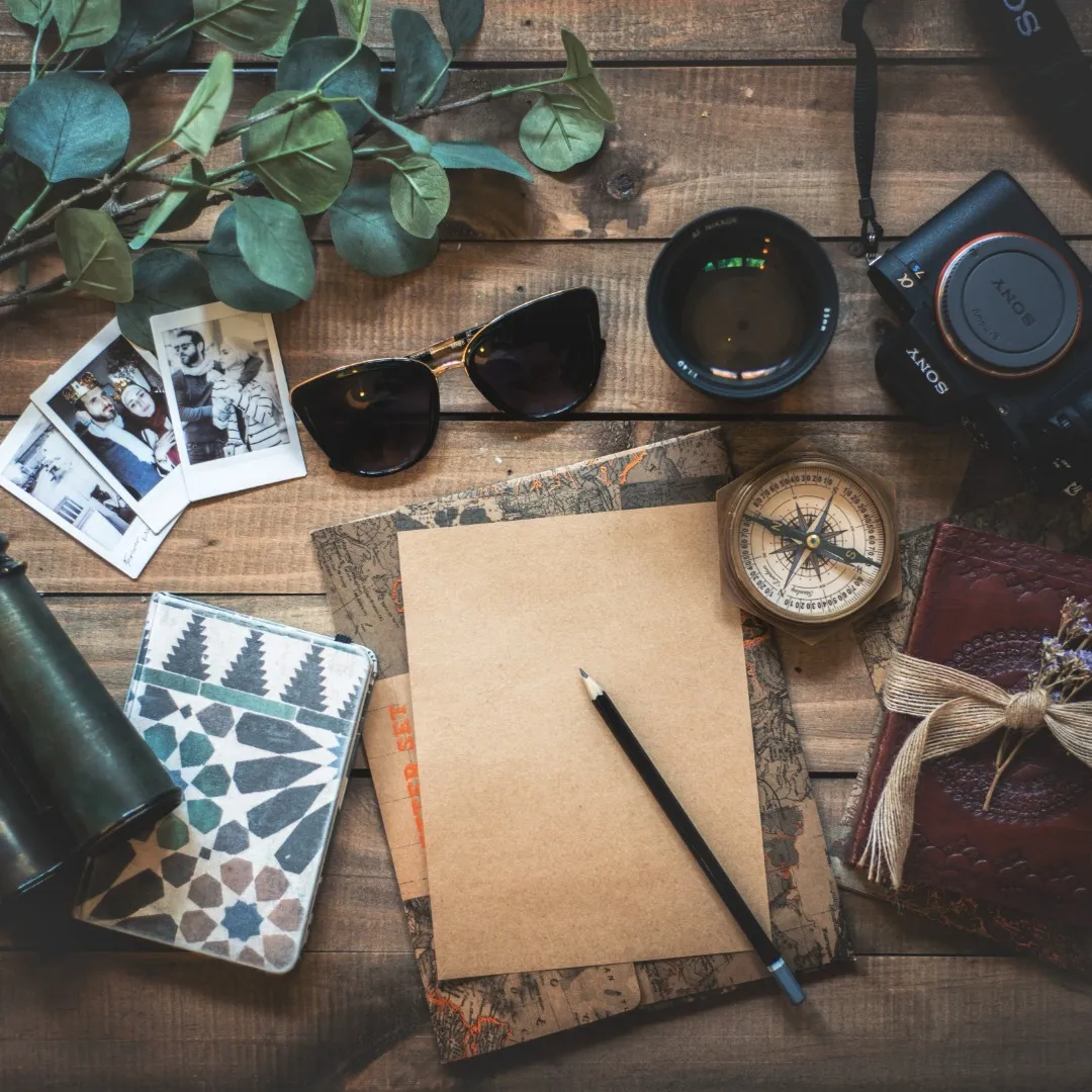 Essentiels de voyage à plat: journal, appareil photo, lunettes de soleil et souvenirs imprimés.
